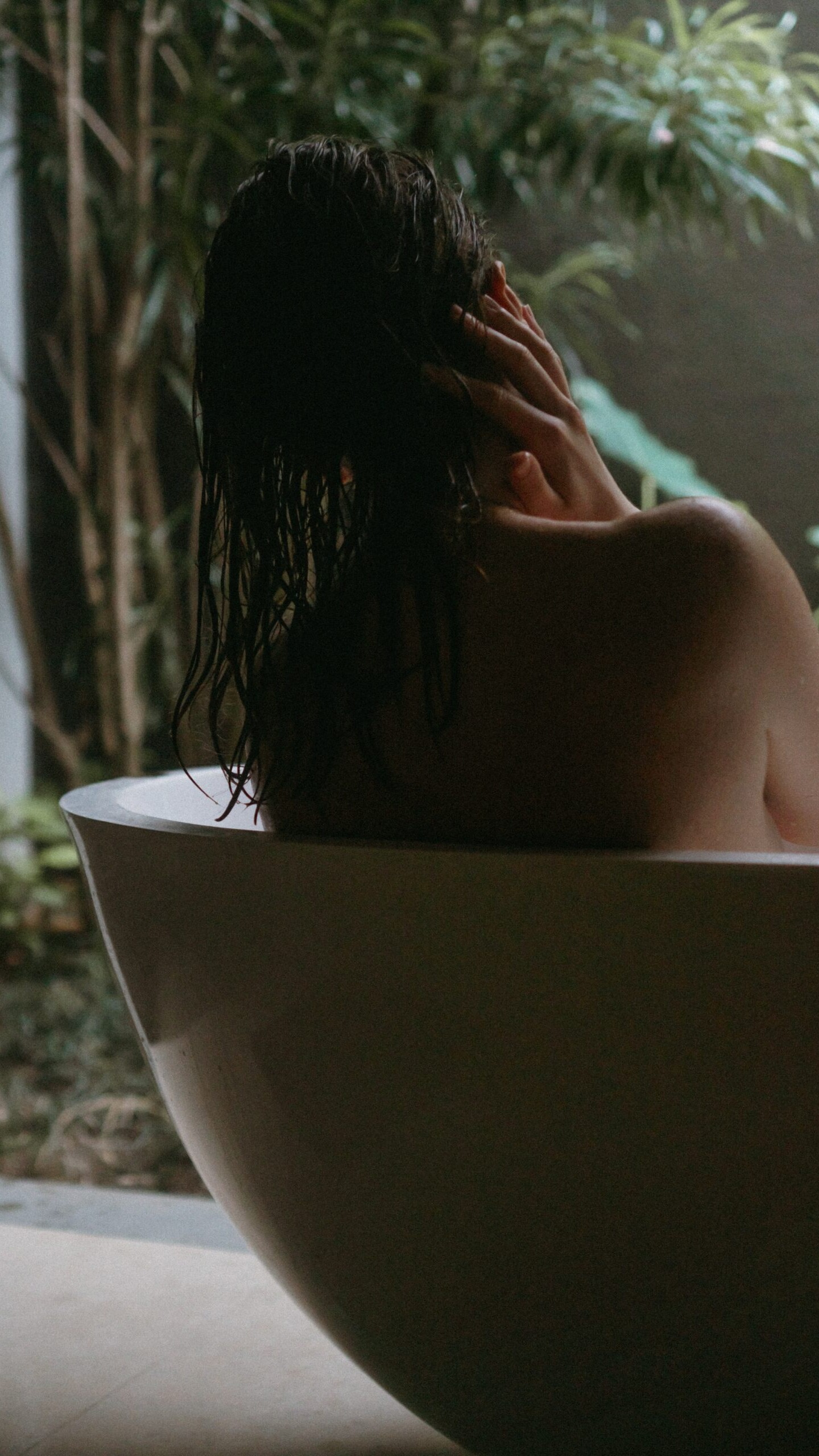 une femme de dos se relaxe dans un bain